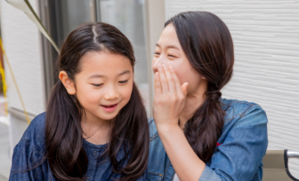 耳打ちする母と喜ぶ娘